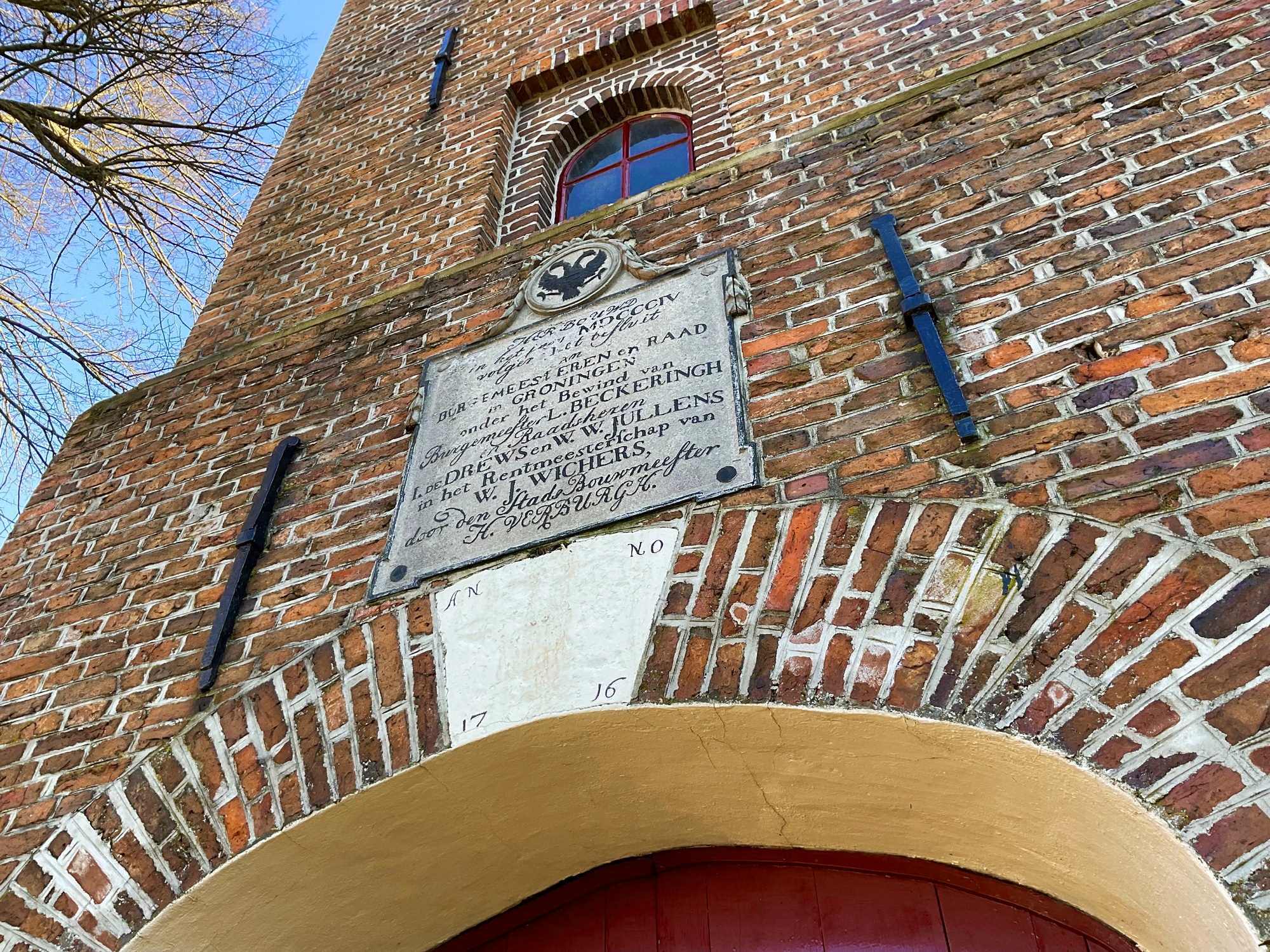 Gedenksteen uit 1804 boven de ingang betreft de herbouw van de toren in 1804. Foto: ©Jur Kuipers, 2023.